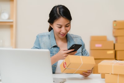 Small business owner checking orders beside packed boxes and a laptop