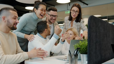 Diverse team high-fiving and celebrating a win together in an open-plan office
