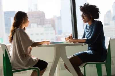 Two professionals in a friendly one-on-one conversation at a table