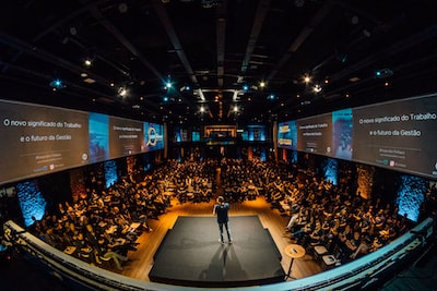 Speaker on stage addressing a large conference audience